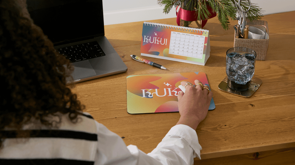 Employee at their desk with branded calendar and mouse pad