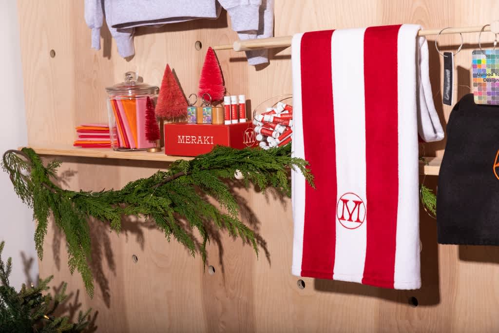 Festive in-store display with branded holiday products, red trees, greenery and a red and white striped towel.