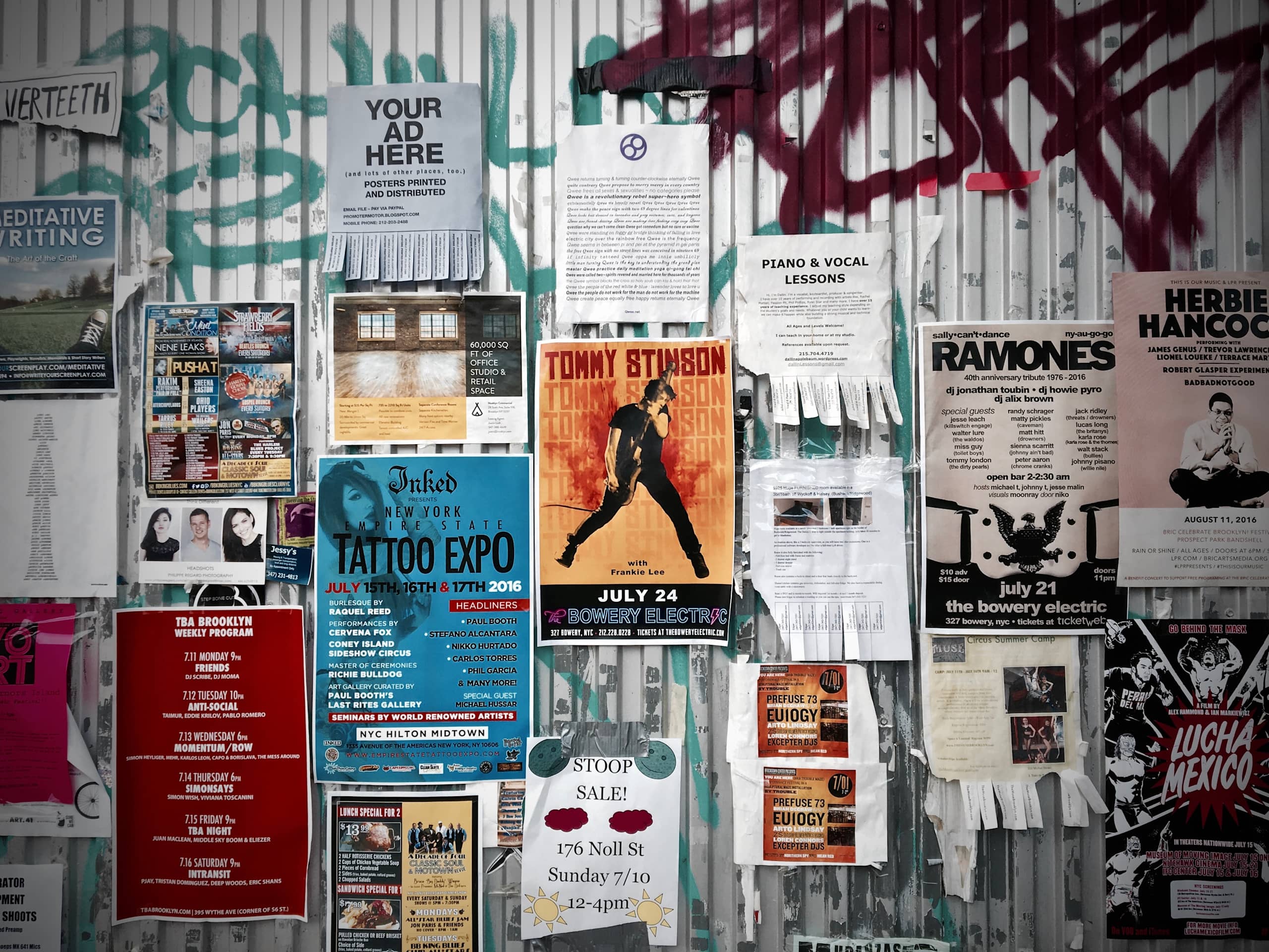 A graffitied wall covered in flyers.